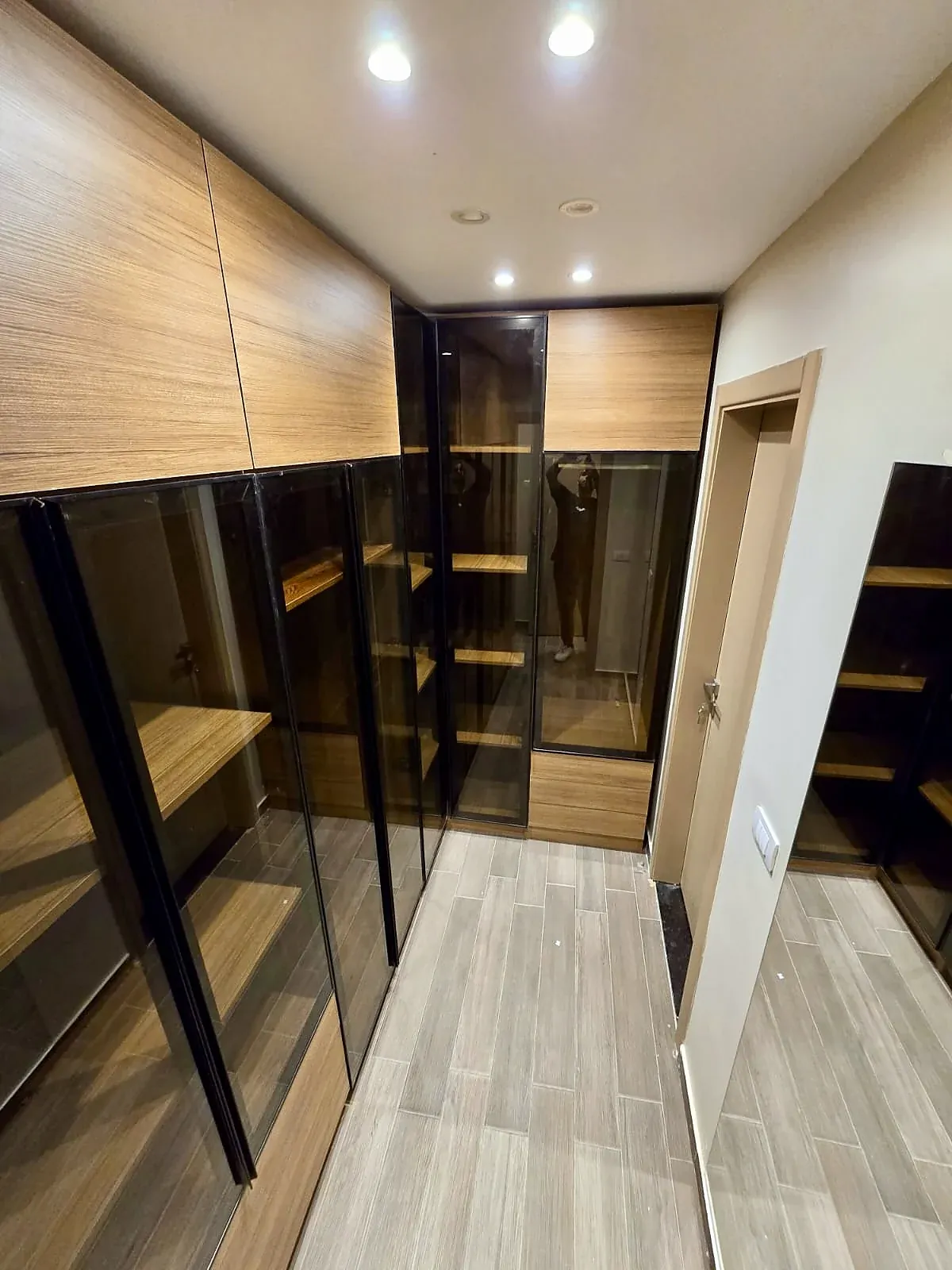 Dressing room with bronze glass doors and wood-finish units, built by Woodify