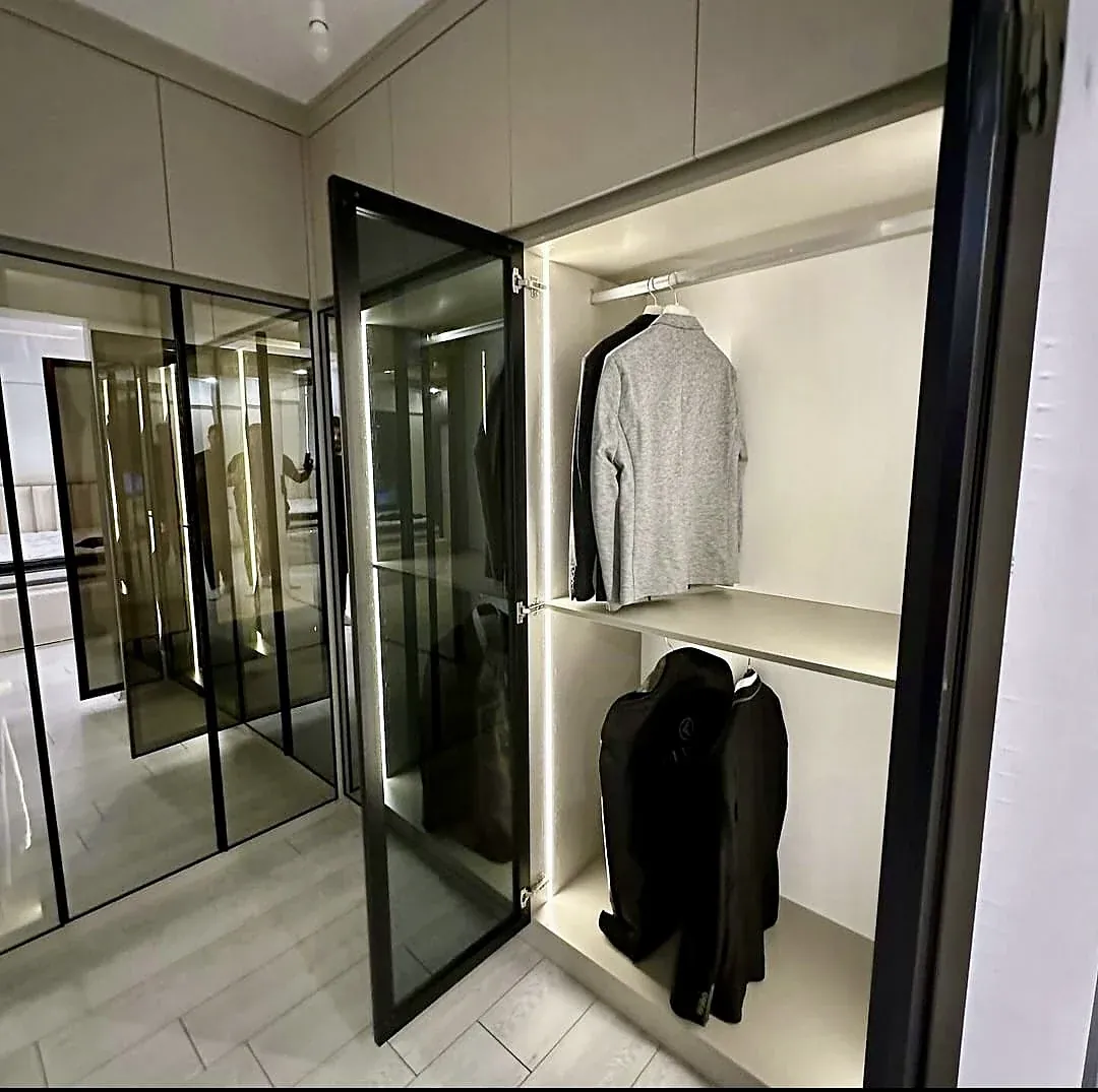 Dressing room with black-framed glass doors and LED lighting inside, built by Woodify
